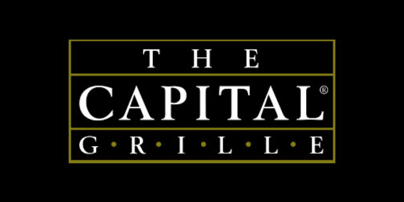 A black rectangle with a gold border and white letters that read  The Capital Grille