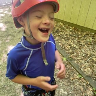 Luke laughing wearing a climbing helmet and gear