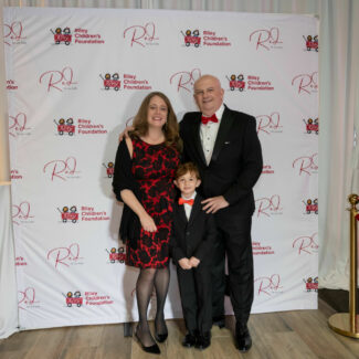 Riley family in front of Riley Red backdrop at Red event