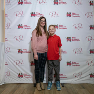 Riley family in front of backdrop with Riley wagons at Red event