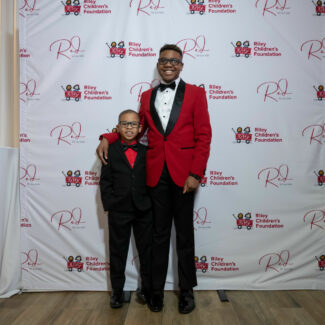 Riley kids in front of backdrop with Riley logos at Riley Red event