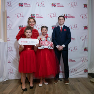 Riley kids posing in front of Riley backdrop at Riley Red event